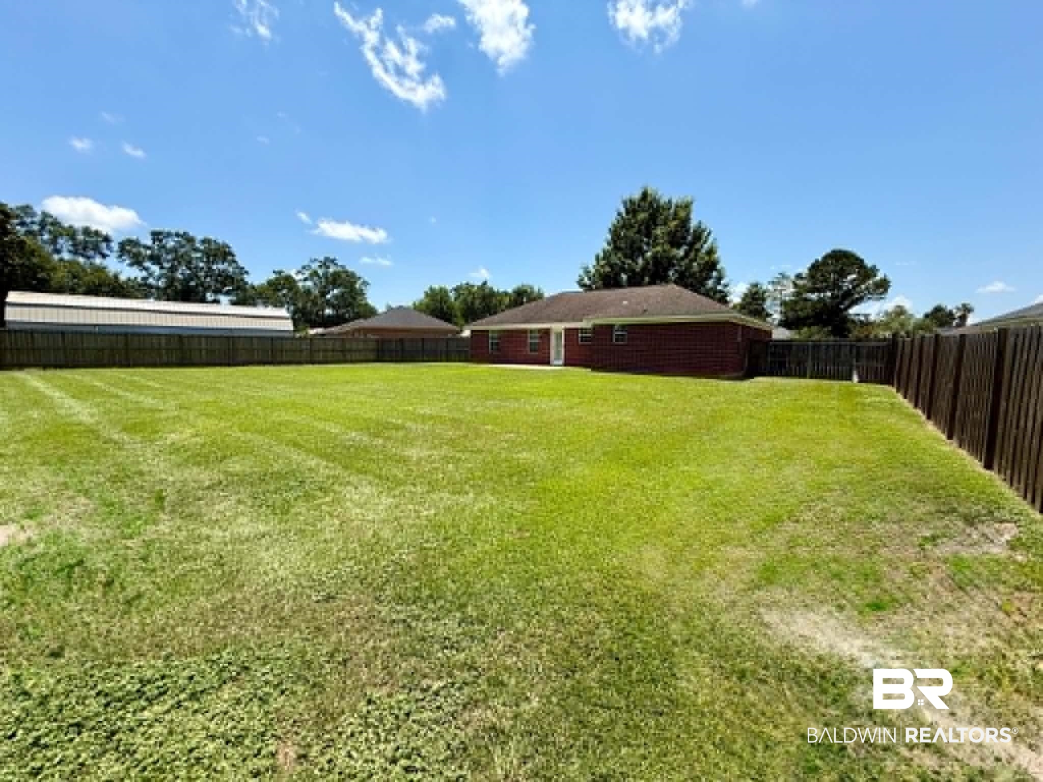 123 Pennbrooke Loop Foley, AL 36535 - Photo 10 of 49 Expansive backyard featuring a lush lawn, privacy fencing, and a brick-sided residence with a shingled roof