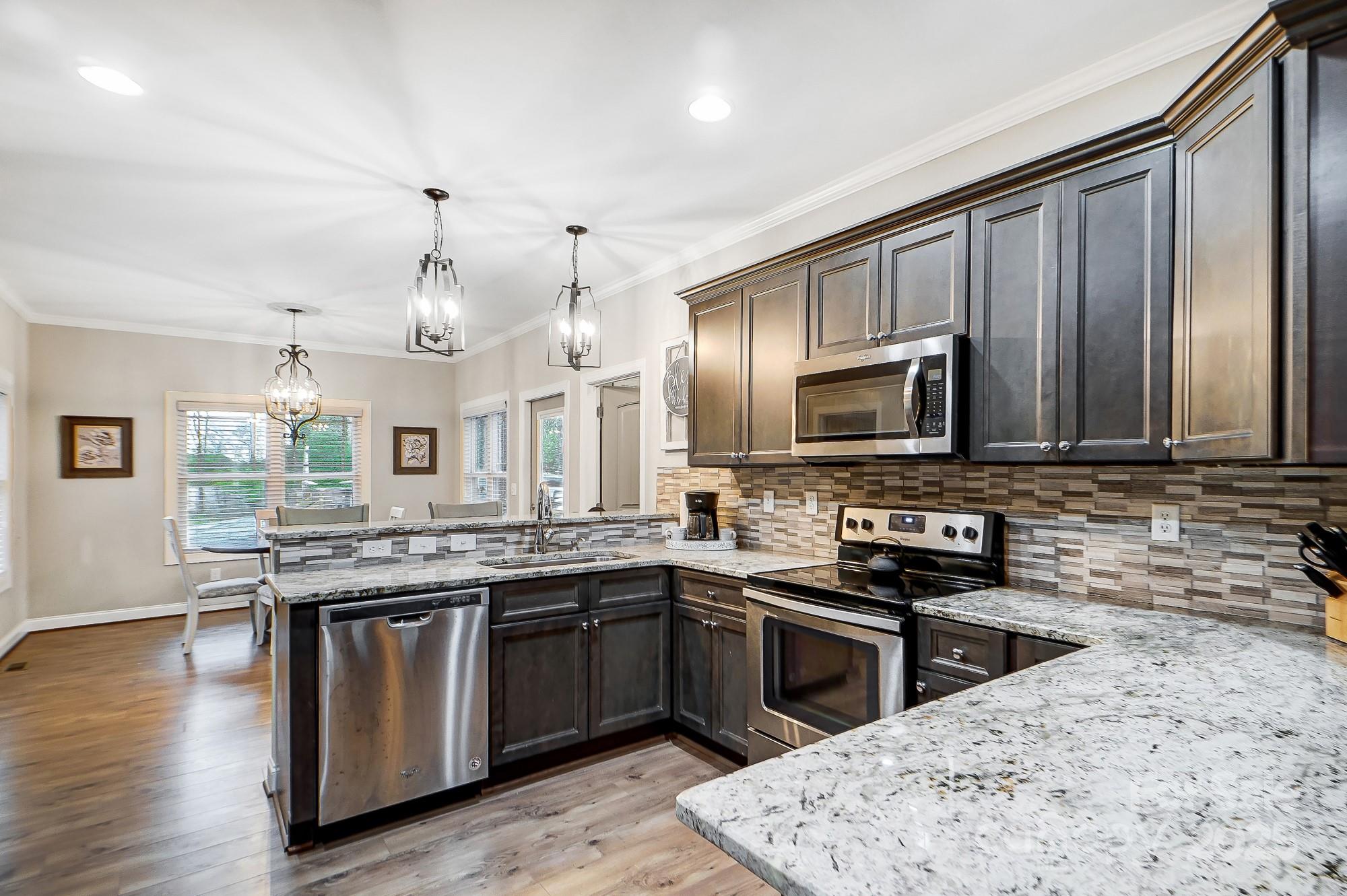 125 Jefferson Drive Locust, NC 28097 - Photo 11 of 27 a kitchen with stainless steel appliances granite countertop a stove a sink dishwasher a microwave oven and a refrigerator with wooden floor