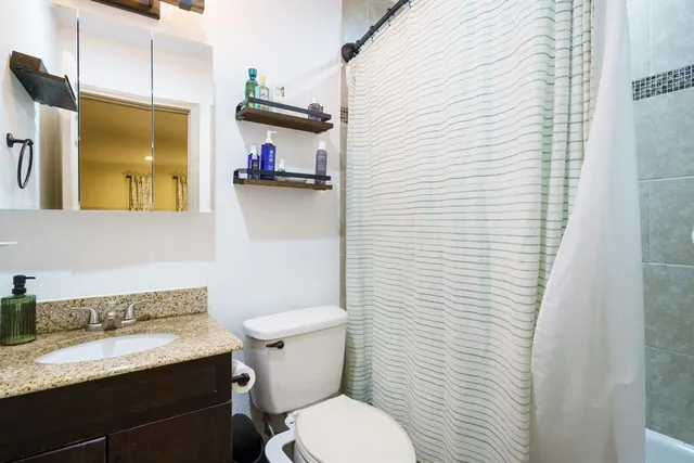 a bathroom with a granite countertop sink and a toilet