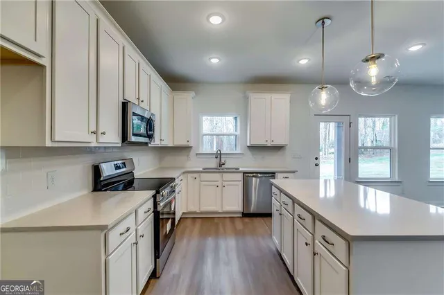 a kitchen with a sink stove cabinets and wooden floor