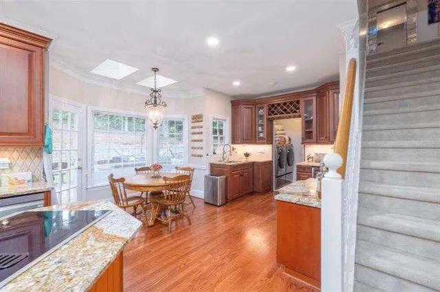 a kitchen with stainless steel appliances granite countertop a refrigerator a sink dishwasher a stove with wooden cabinets and floor