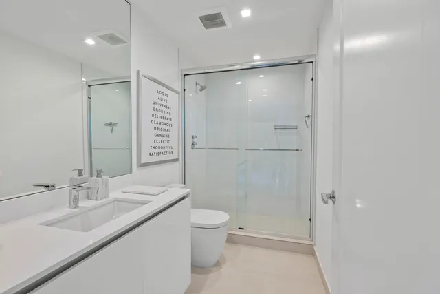 a bathroom with a shower sink vanity mirror and toilet