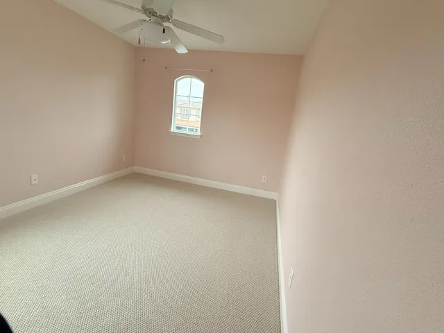 an empty room with a chandelier fan and windows