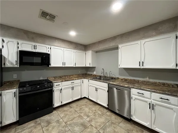 a kitchen with granite countertop white cabinets stainless steel appliances and a sink