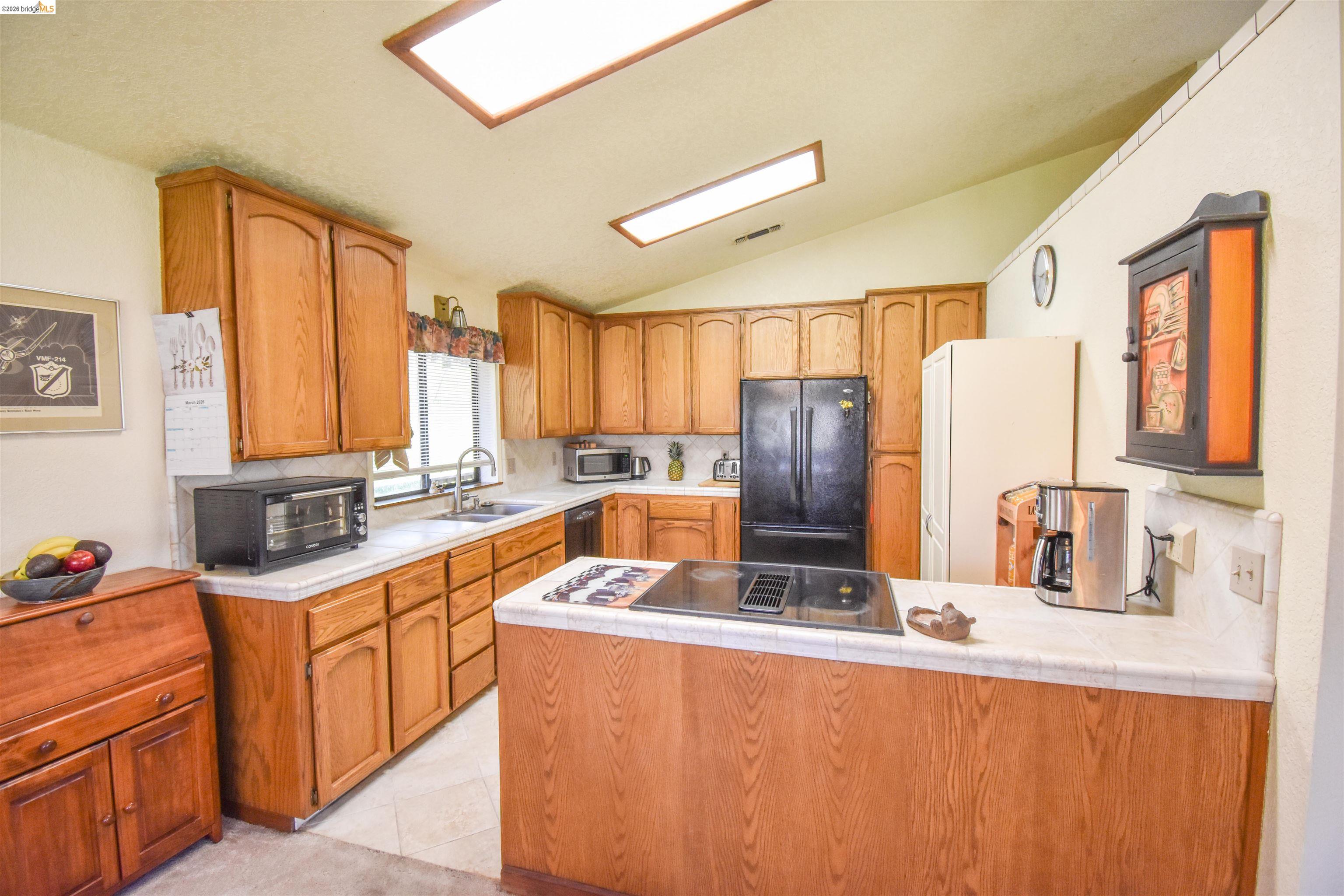 15170 Potato Ranch Road Sonora, CA 95370 - Photo 16 of 49 Kitchen with tile counters, a peninsula, vaulted ceiling, stainless steel appliances, and wood finish cabinetry