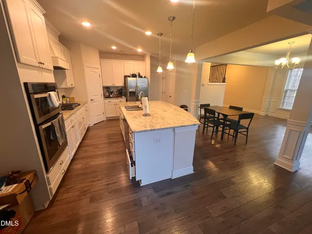a kitchen with kitchen island granite countertop wooden floors and white cabinets