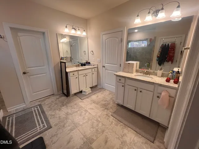 a spacious bathroom with a double vanity sink a mirror and a shower