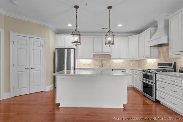 a kitchen with stainless steel appliances granite countertop a sink a stove a refrigerator and island with wooden floor