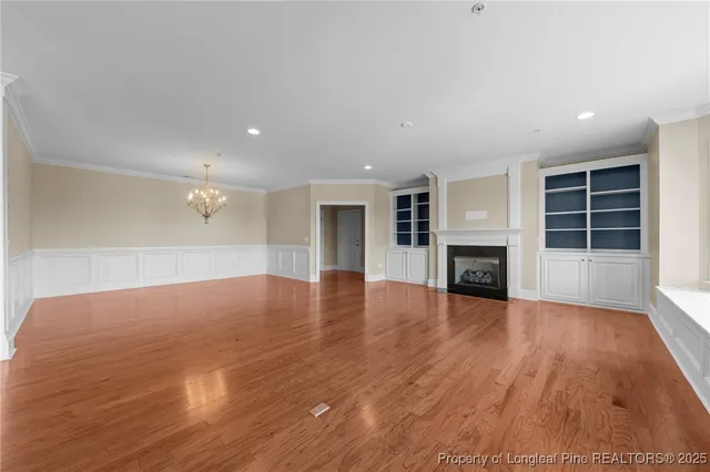 an empty room with wooden floor fireplace and windows