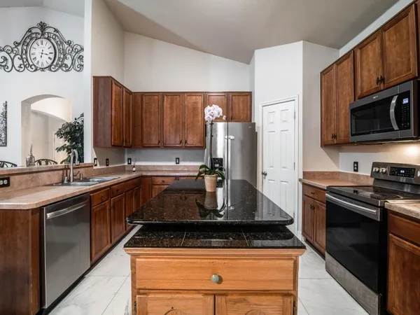 a kitchen with stainless steel appliances granite countertop a stove microwave and refrigerator