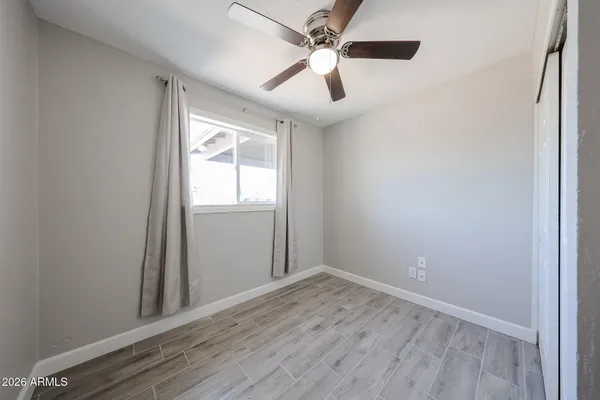 an empty room with wooden floor fan and windows
