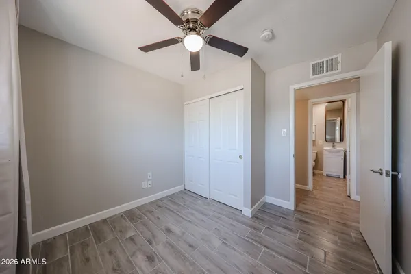 an empty room with wooden floor and a ceiling fan