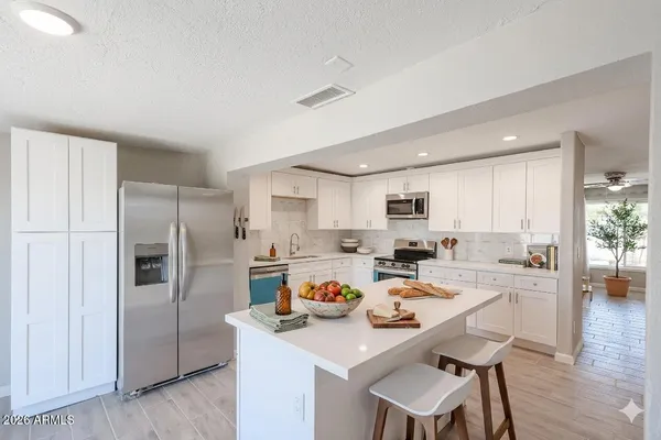 a kitchen with a refrigerator a stove a sink and white cabinets with wooden floor