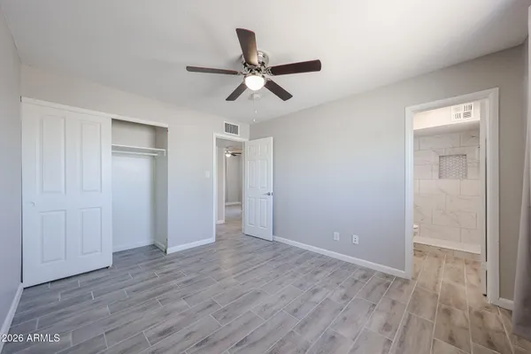 a view of empty room with wooden floor and ceiling fan