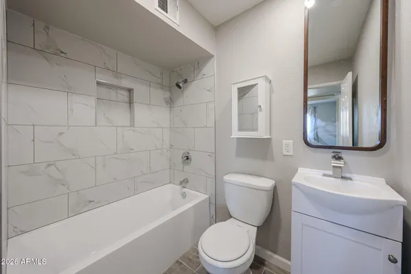 a bathroom with a toilet sink vanity tub and mirror