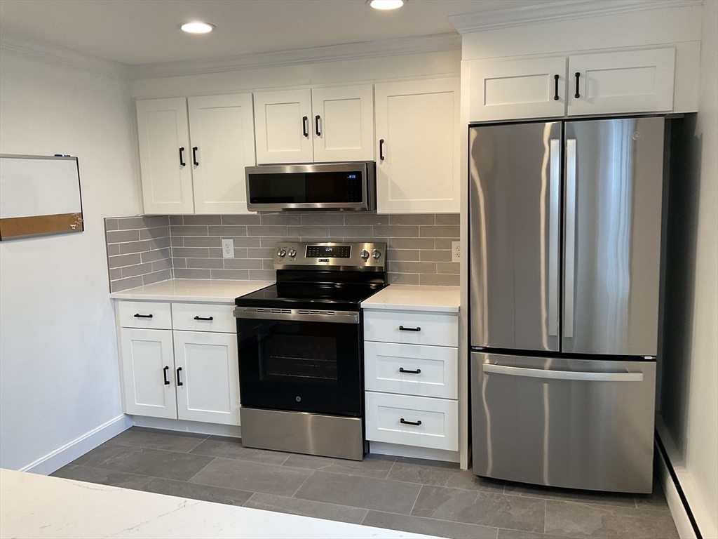 26 Summer Street, Unit 8 Marblehead, MA 01945 - Photo 5 of 23 a kitchen with white cabinets and stainless steel appliances