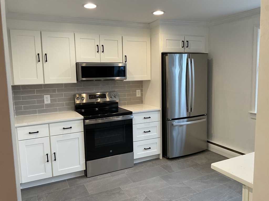 26 Summer Street, Unit 8 Marblehead, MA 01945 - Photo 6 of 23 a kitchen with stainless steel appliances a refrigerator stove and white cabinets