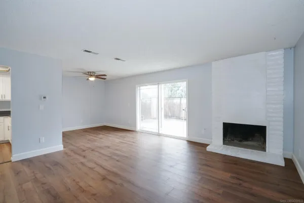 a view of empty room with wooden floor and fireplace