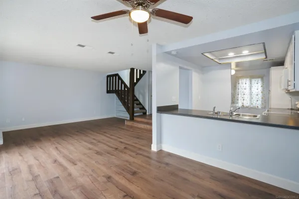 a view of a kitchen with wooden floor and a ceiling fan