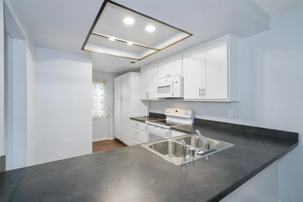 a kitchen with granite countertop a sink a stove and cabinets