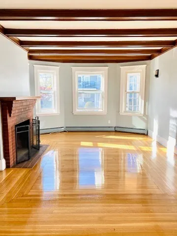 a view of a living room with stainless steel appliances wooden floor and a fireplace