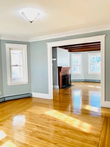 a view of empty room with wooden floor and fan
