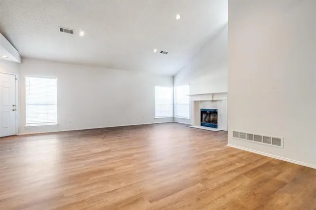 an empty room with wooden floor and fireplace