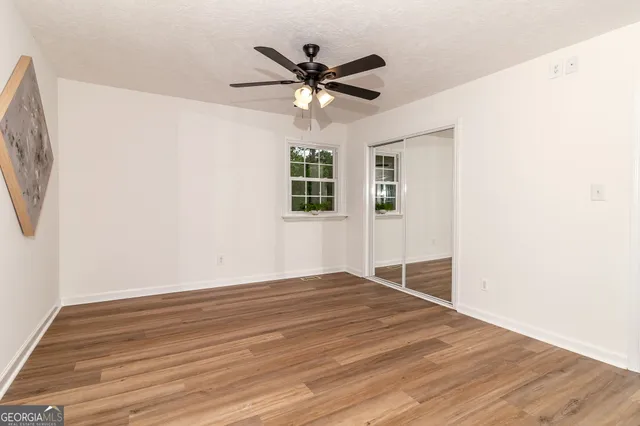 a view of an empty room with a window and wooden floor