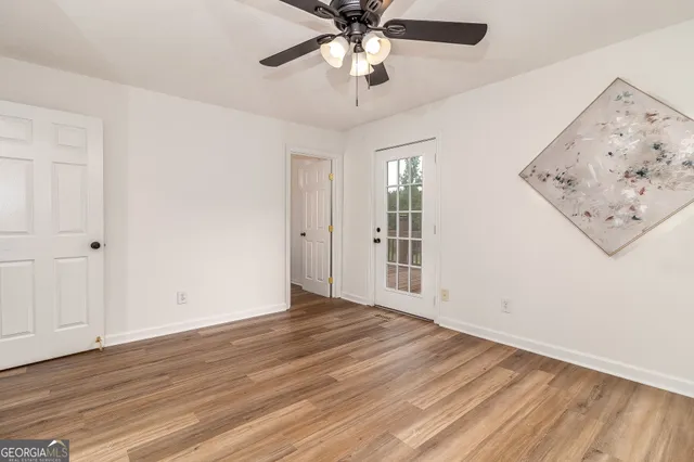 a view of an empty room with wooden floor fireplace and a window