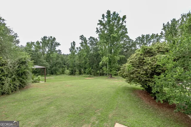 a view of a yard in front of a house with large windows