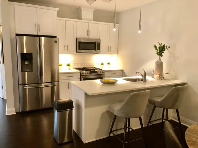 a kitchen with stainless steel appliances a dining table chairs refrigerator and microwave