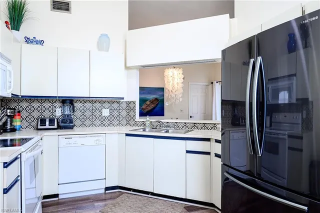 a kitchen with a stove and white cabinets with wooden floor