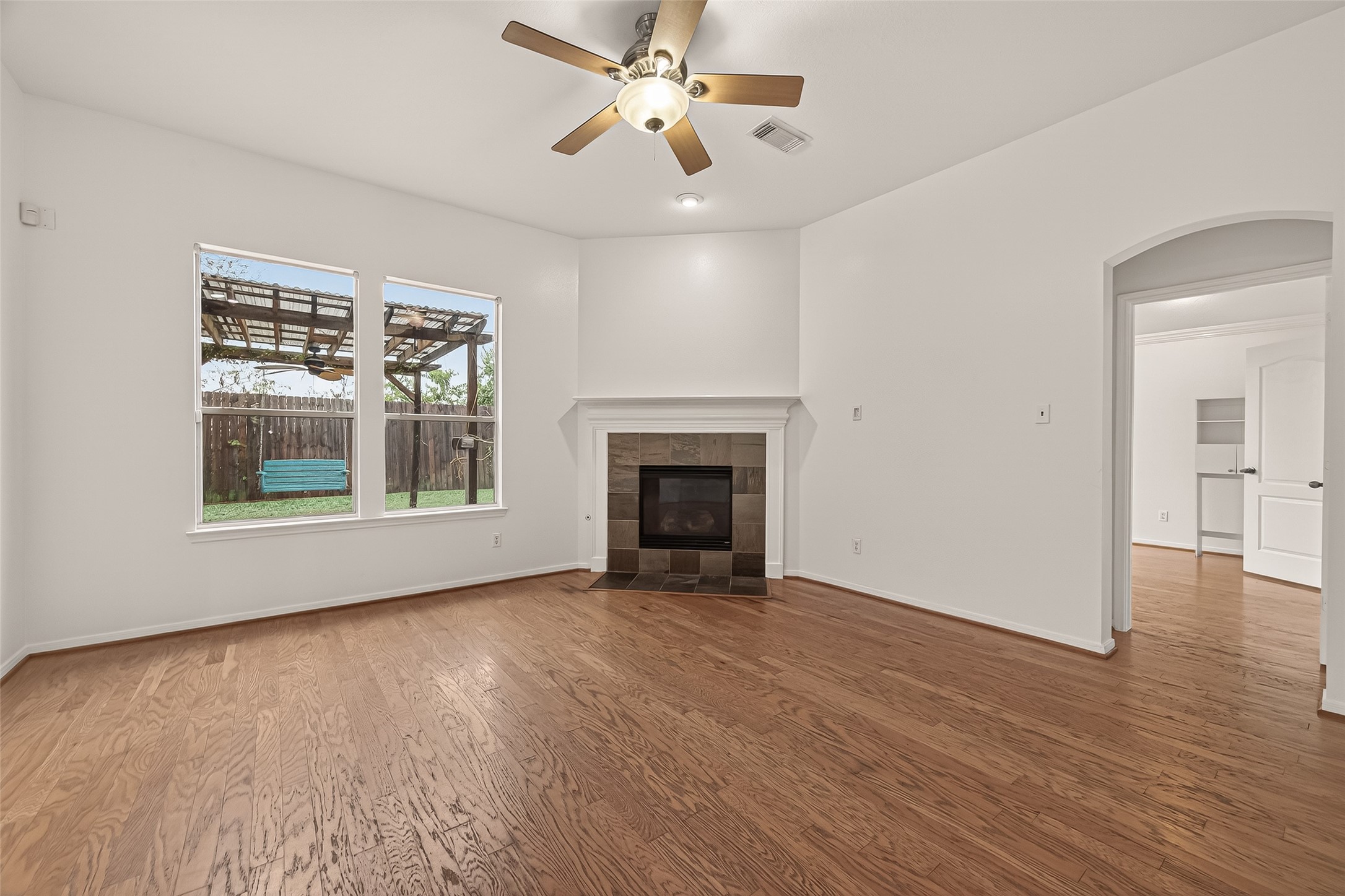 2704 Hewn Rock Way Pearland, TX 77584 - Photo 12 of 40 an empty room with wooden floor a ceiling fan and windows