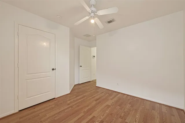 an empty room with wooden floor and fan
