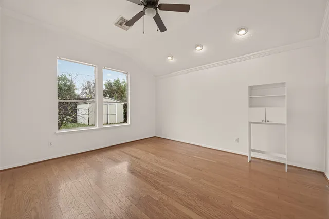 a view of an empty room with a window and wooden floor