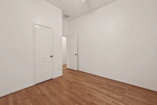 a view of an empty room with wooden floor and closet