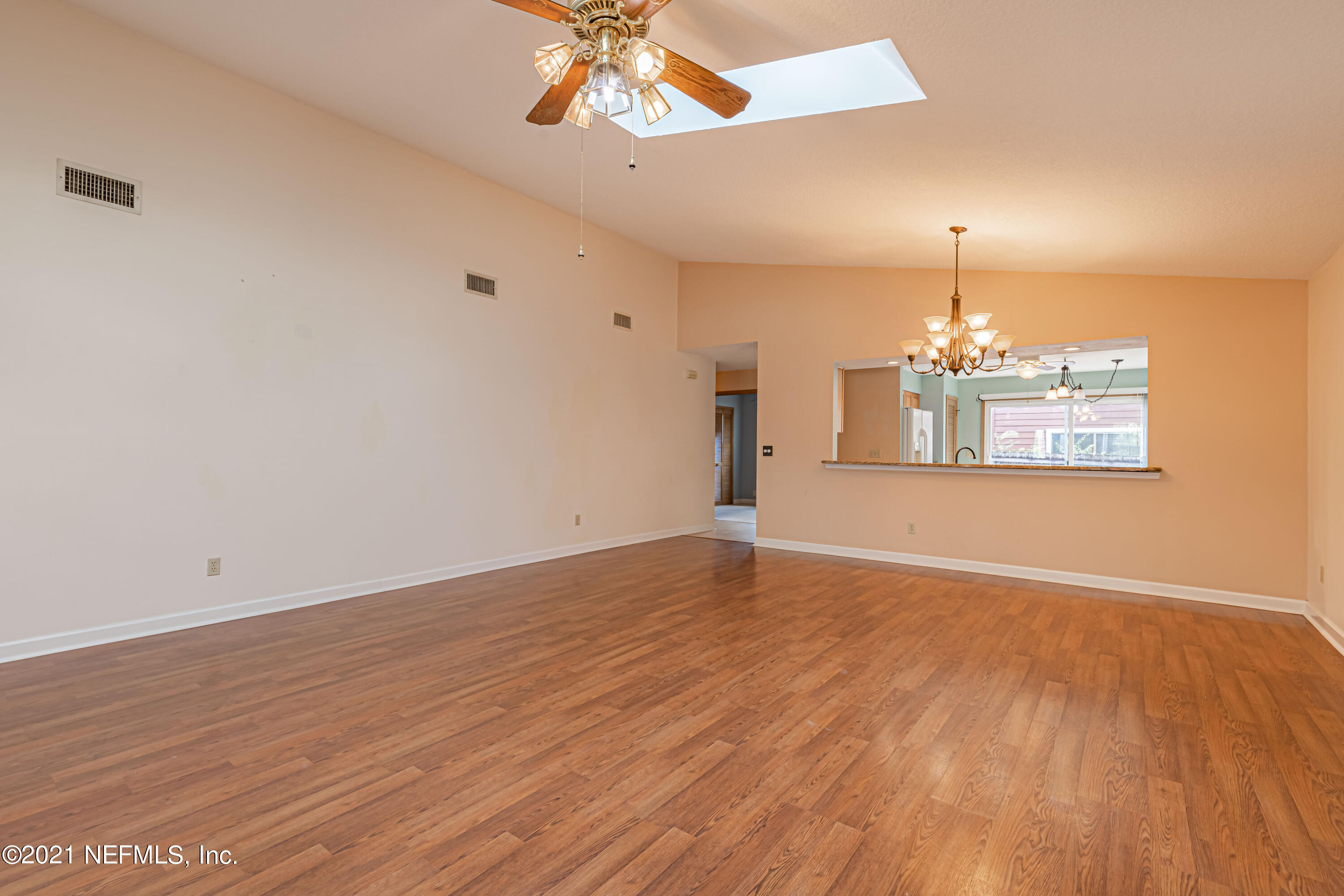 5416 Spring Brook Road Jacksonville, FL 32277 - Photo 7 of 27 an empty room with wooden floor chandelier fan and windows