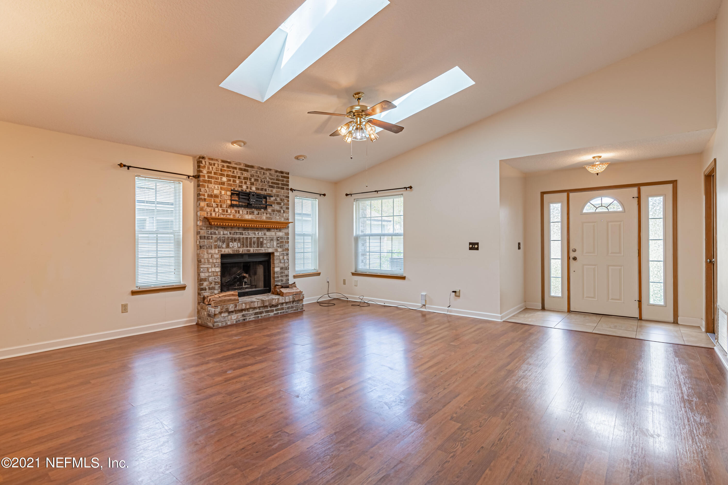 5416 Spring Brook Road Jacksonville, FL 32277 - Photo 8 of 27 an empty room with wooden floor fireplace and windows