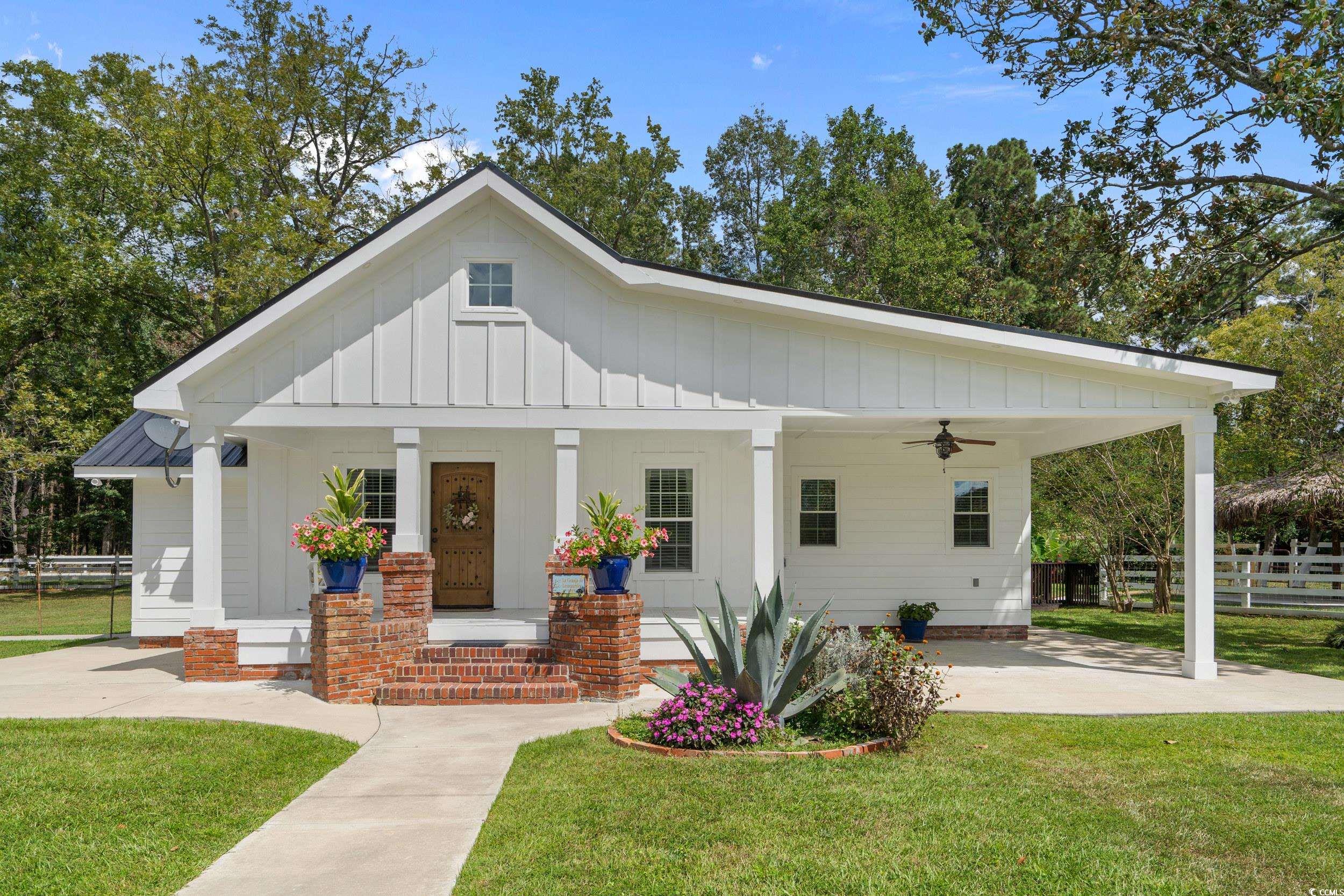 View of front of home with board and batten siding, a porch, a ceiling fan, and a carport