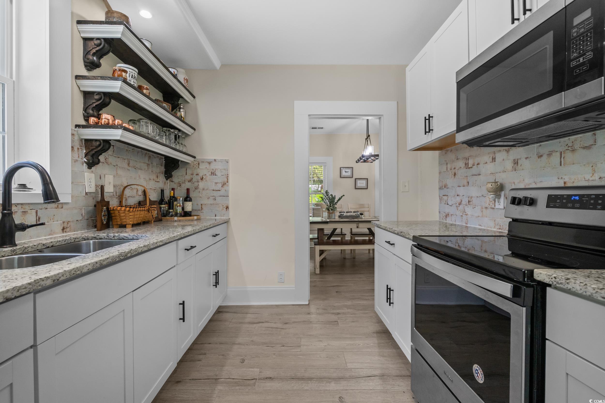 2323 Main Street Loris, SC 29569 - Photo 27 of 40 Kitchen featuring open shelves, stainless steel appliances, white cabinets, light stone counters, and decorative backsplash