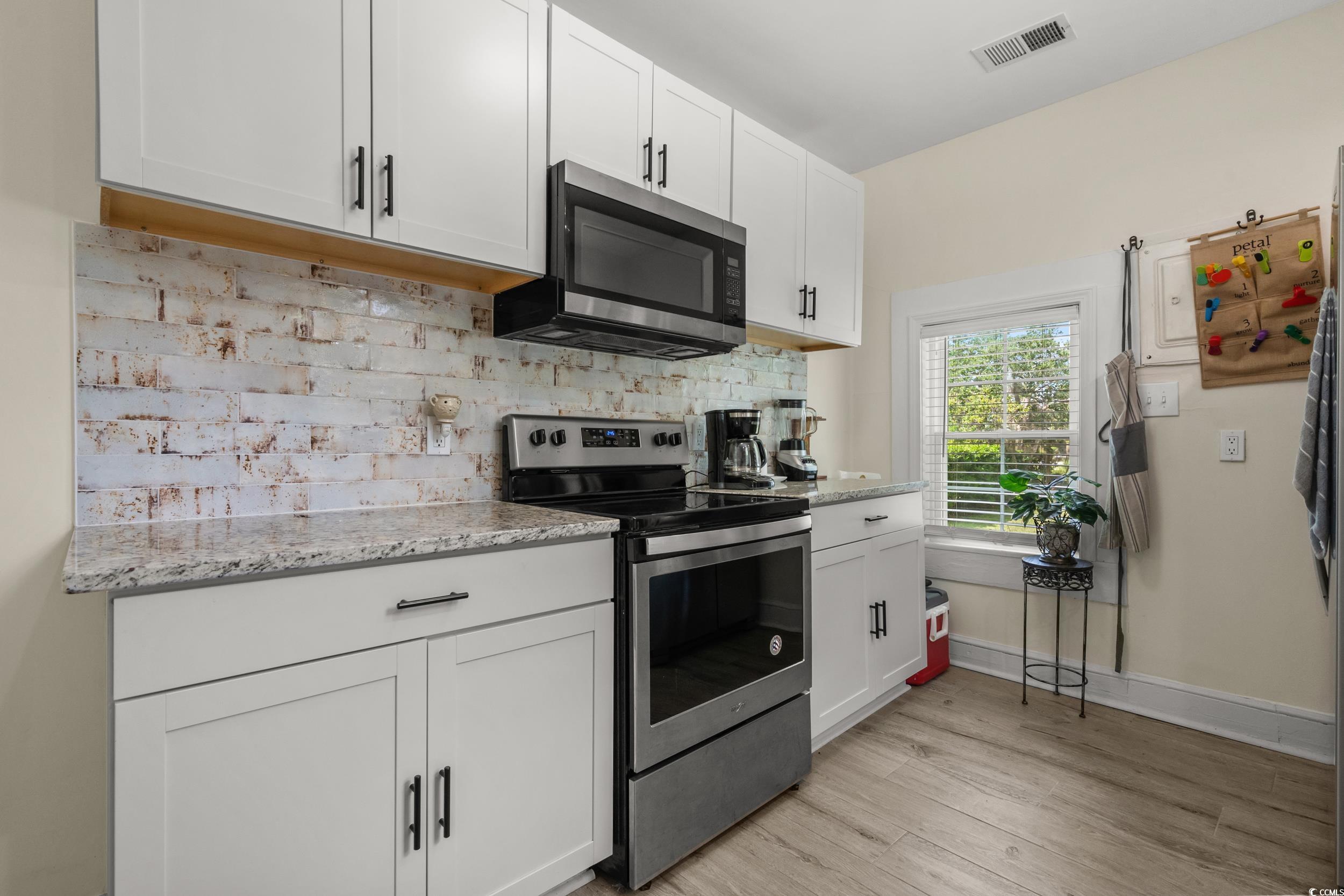 2323 Main Street Loris, SC 29569 - Photo 29 of 40 Kitchen with stainless steel appliances, white cabinets, light stone countertops, and light wood-style flooring