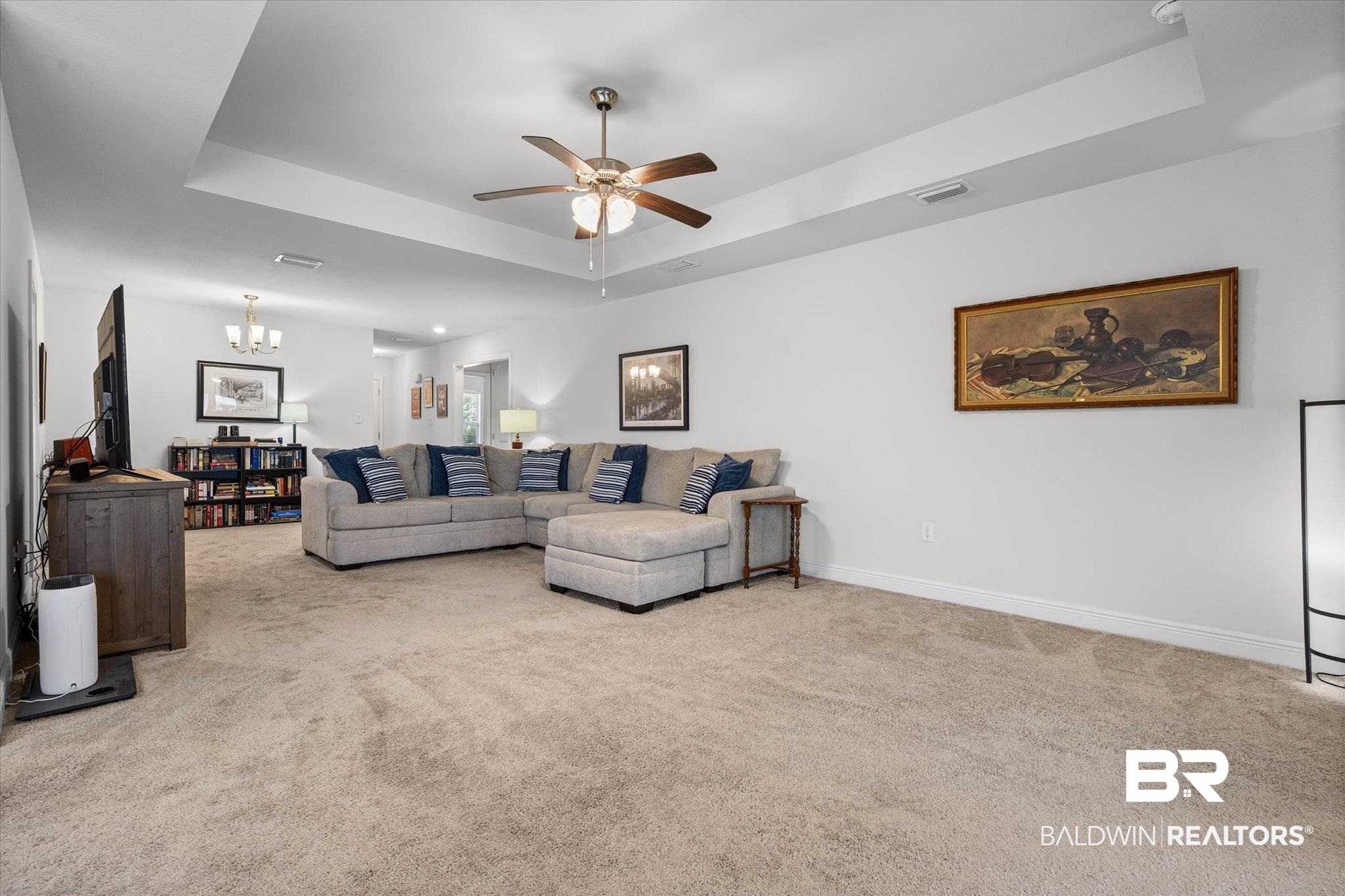 22420 Respite Lane Foley, AL 36535 - Photo 3 of 35 Spacious living area featuring neutral carpet flooring, a tray ceiling with a ceiling fan, and white baseboards