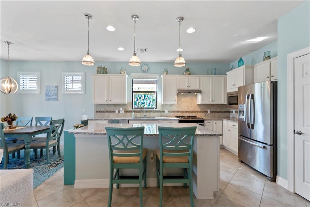 6264 Victory Drive Immokalee, FL 34142 - Photo 3 of 44 a kitchen with stainless steel appliances kitchen island granite countertop a table chairs and a refrigerator