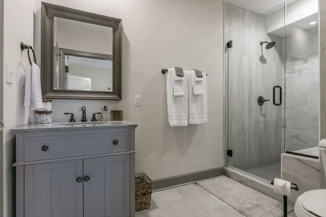 a bathroom with a sink vanity granite toilet and shower
