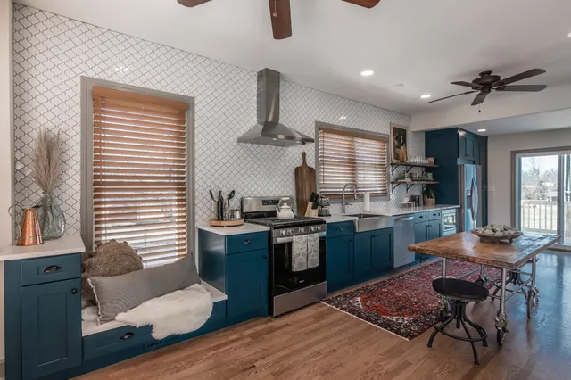 a kitchen with stainless steel appliances kitchen island granite countertop wooden cabinets a dining table and chairs