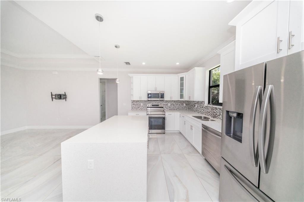 808 37th Avenue Northwest Naples, FL 34120 - Photo 6 of 27 a large kitchen with white cabinets and stainless steel appliances