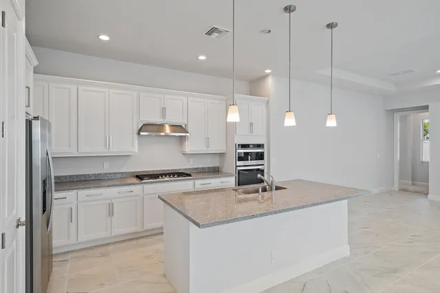 a kitchen with stainless steel appliances granite countertop a sink a counter space and living room view
