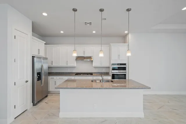 a large white kitchen with lots of counter space cabinets and appliances