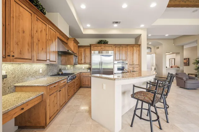 a kitchen with stainless steel appliances granite countertop table chairs sink and cabinets