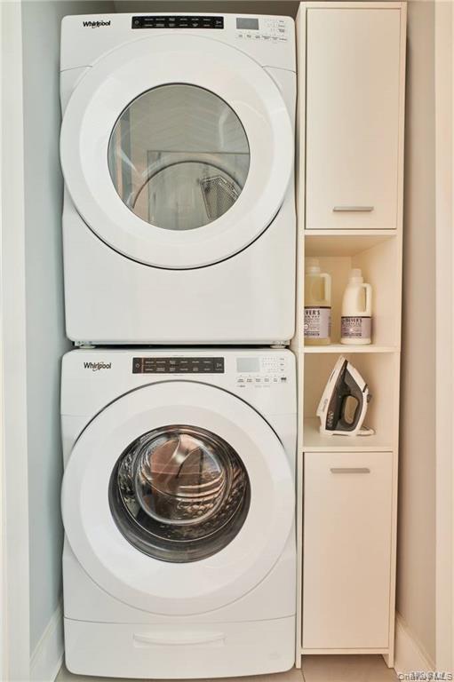 100 Garvies Point Road, Unit 1202 Glen Cove, NY 11542 - Photo 8 of 14 Laundry room featuring stacked washer / drying machine and tile patterned flooring